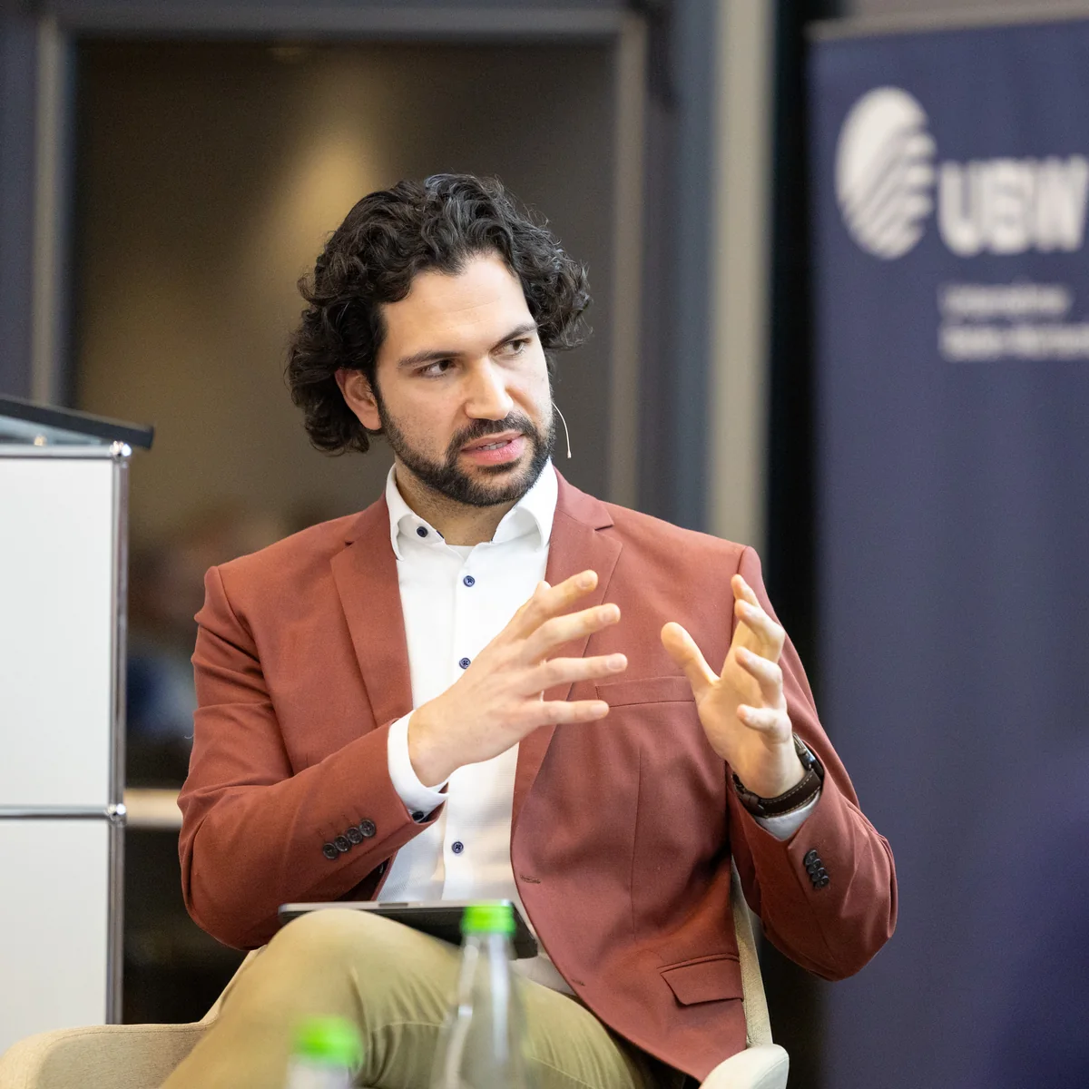Joti Fotiadis mit Headset und gestikulierenden Händen beim Energiepolitischen Forum
