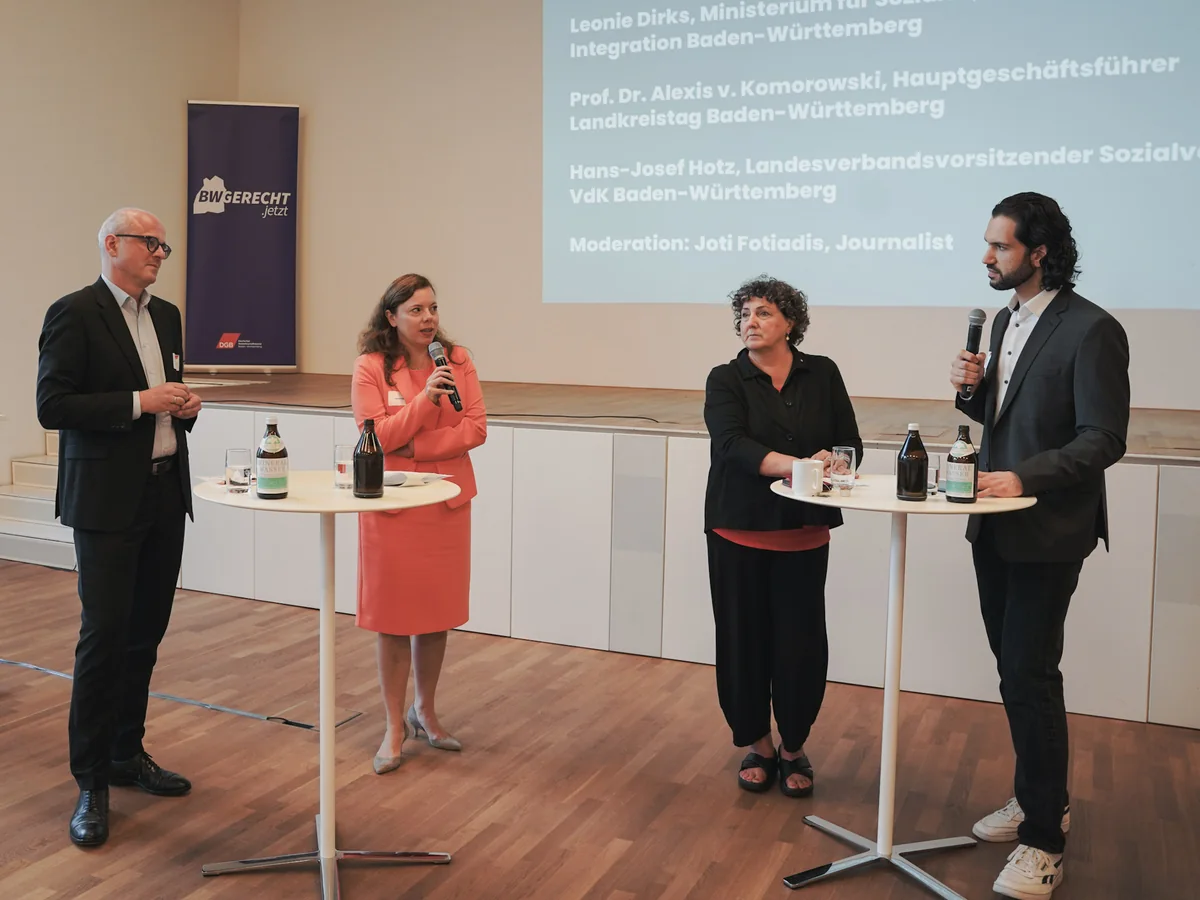 Joti Fotiadis rechts mit Mikrofon in einer Gesprächsrunde der DGB-Gesundheitskonferenz